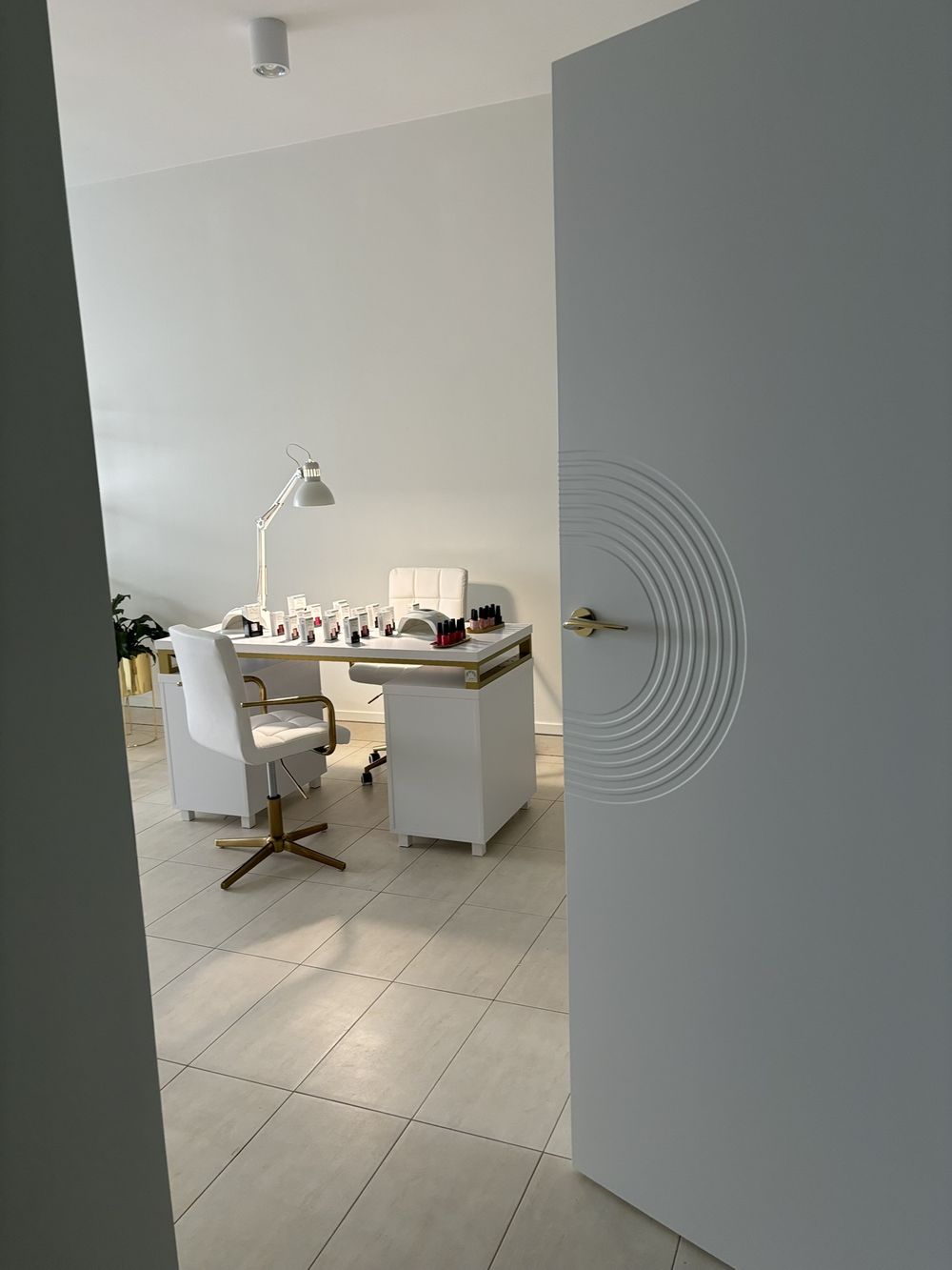 Widok na stanowisko manicure przez otwarte drzwi gabinetu